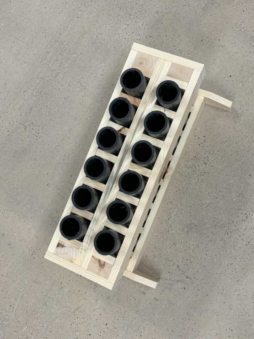 Top view of a white rack holding twelve black cylindrical objects arranged in two columns.